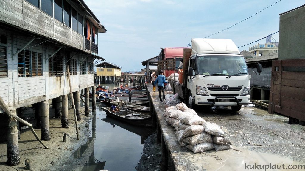 Workers unloading goods from lorry trucks at Kukup Fisherman's Jetty